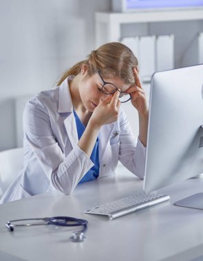 Genç kadın doktor bilgisayar ile çalıştıktan sonra yorgun