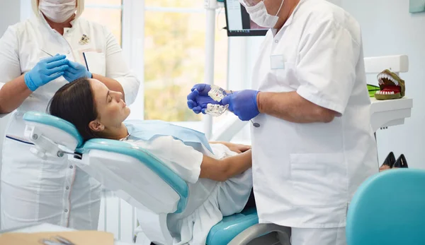 Médico dentista trata dentes de uma bela jovem paciente . — Fotografia de Stock