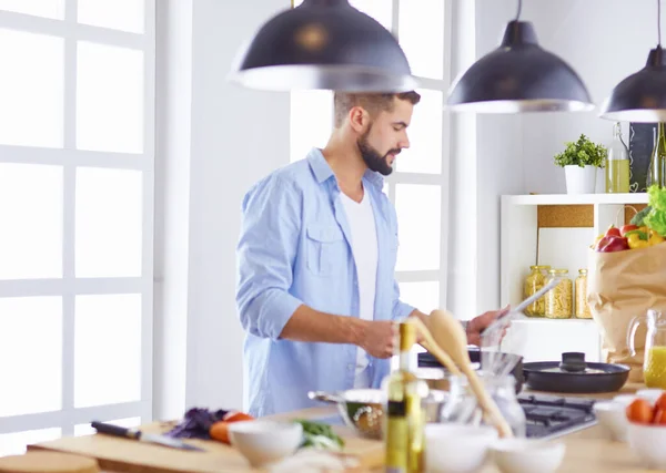 Улыбающийся и уверенный шеф-повар стоит на большой кухне — стоковое фото