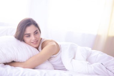güzel genç kadın yatakta sabah tadını çıkarma. Güzel Model yüz kamera seksi görünüyor