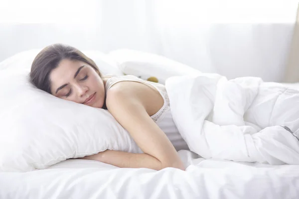 Vacker ung kvinna basking i sängen på morgonen. Vacker modell ansikte ser sexig i kameran — Stockfoto