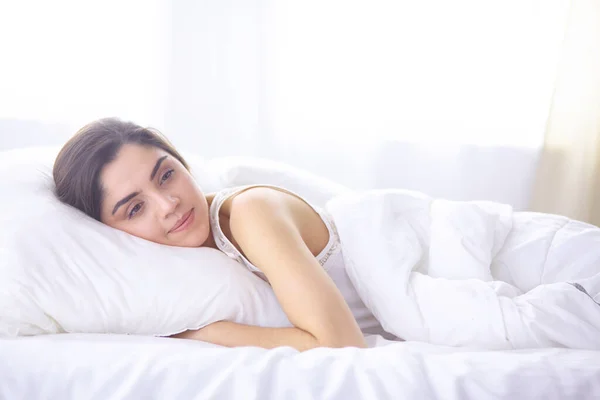 Vacker ung kvinna basking i sängen på morgonen. Vacker modell ansikte ser sexig i kameran — Stockfoto