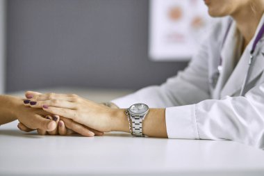 Kadın doktor hastayı sakinleştirir ve elini tutar