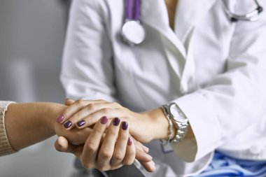 Kadın doktor hastayı sakinleştirir ve elini tutar