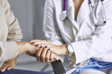 Kadın doktor hastayı sakinleştirir ve elini tutar