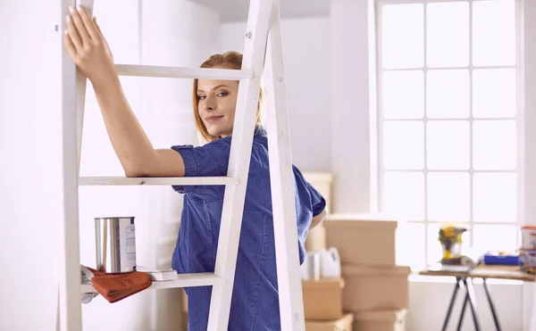 Vacker ung kvinna på en vit trappstege i trä. Redo att reparera rummet. Begreppet hushållsarbete för kvinnor — Stockfoto
