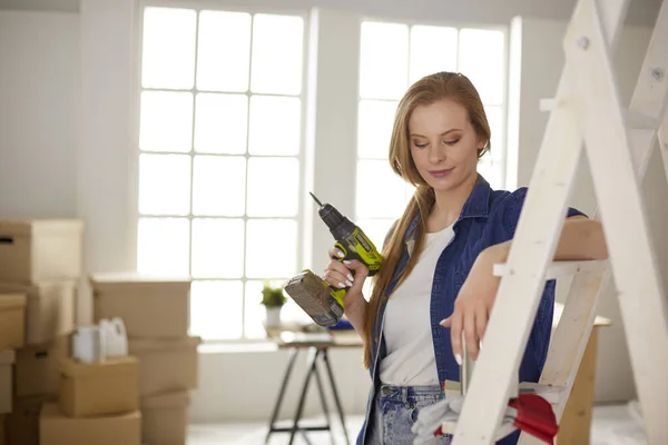 Bella giovane donna su una scala di legno bianca. Pronto a riparare la stanza. Donne concetto di lavori domestici — Foto Stock