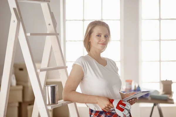 Hermosa joven en una escalera de madera blanca. Listo para reparar la habitación. Concepto de tareas domésticas — Foto de Stock