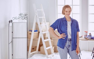 Beyaz tahta bir merdiven üzerinde güzel bir genç kadın. Odayı onarmaya hazırız. Kadın ev işi konsepti