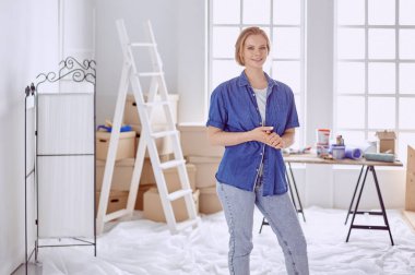 Beyaz tahta bir merdiven üzerinde güzel bir genç kadın. Odayı onarmaya hazırız. Kadın ev işi konsepti