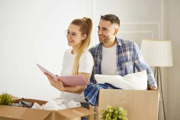 Porträtt av lyckliga par tittar på bärbar dator tillsammans sitter i nytt hus, omgiven av lådor — Stockfoto