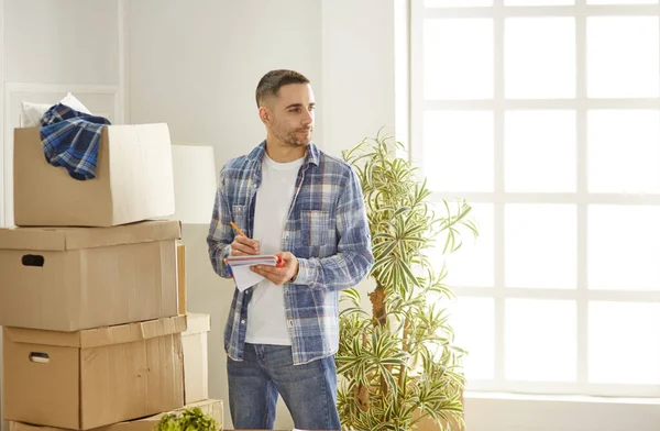 Красивый мужчина с коробками в новой квартире после переезда — стоковое фото