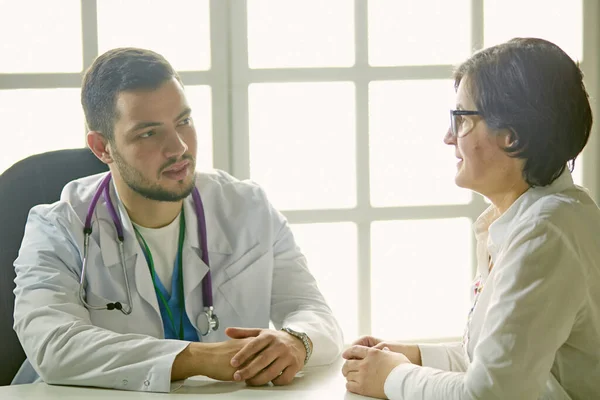 Mladý doktor mluví s pacientem v kanceláři — Stock fotografie