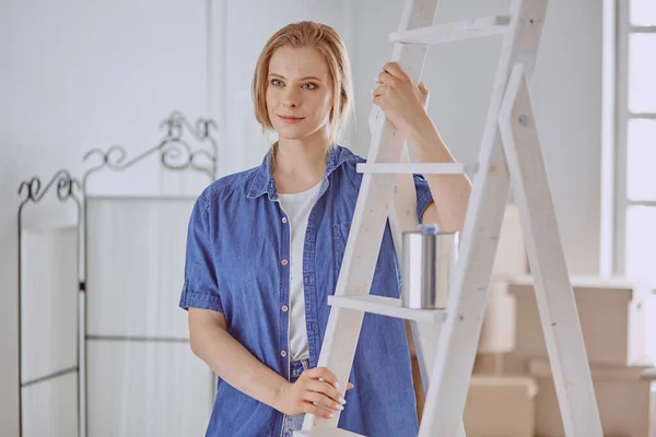 Vacker ung kvinna på en vit trappstege i trä. Redo att reparera rummet. Begreppet hushållsarbete för kvinnor — Stockfoto