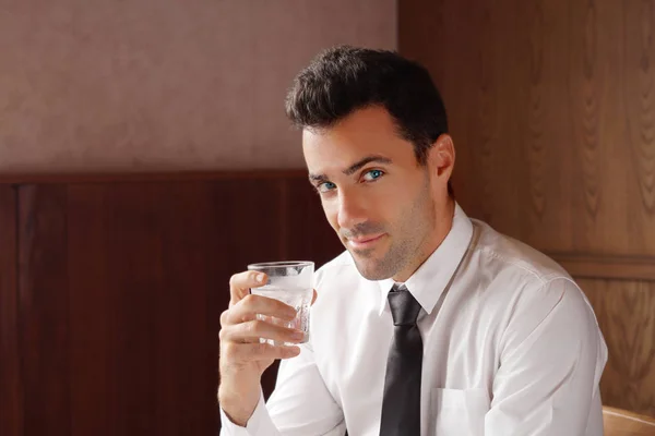 Good looking businessman holding a glass of water and smile.Water is key for anti aging concept. Stock photo — Stock Photo, Image