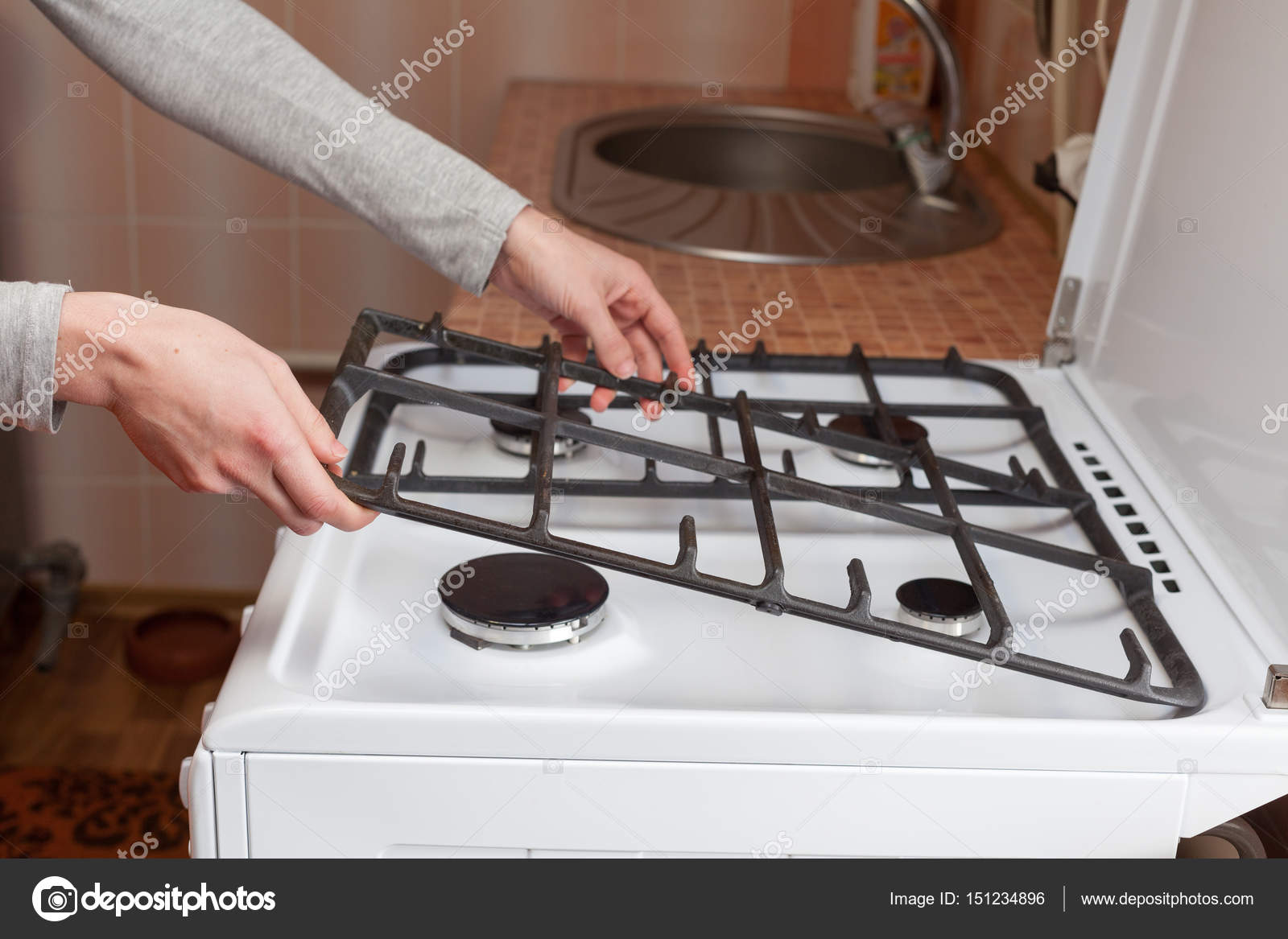 Housewife hold metal grates to clean the dirty kitchen gas stove