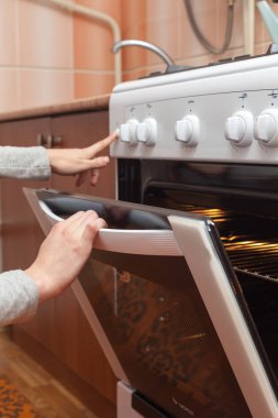 Kadın el gaz sobası kızartma denetlemek için fırın kapı açma, kapatma.