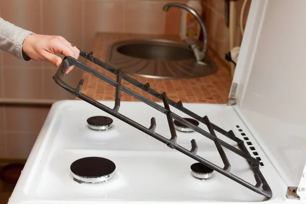 Dona de casa segurar grades de metal para limpar o fogão a gás da cozinha suja . — Fotografia de Stock
