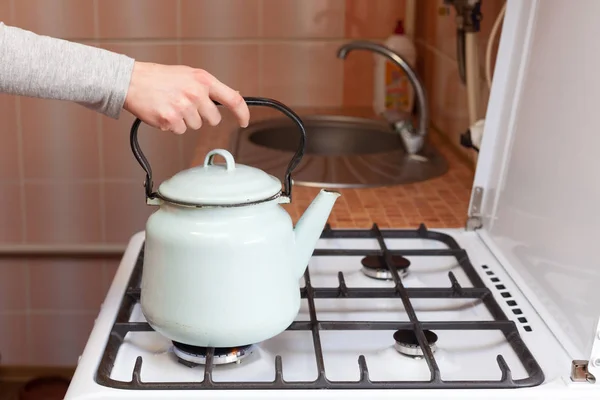 女孩把蓝色水壶放上一个厨房煤气炉. — 图库照片