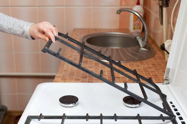 Домогосподарка тримає металеві решітки для очищення брудної кухонної газової плити . — стокове фото