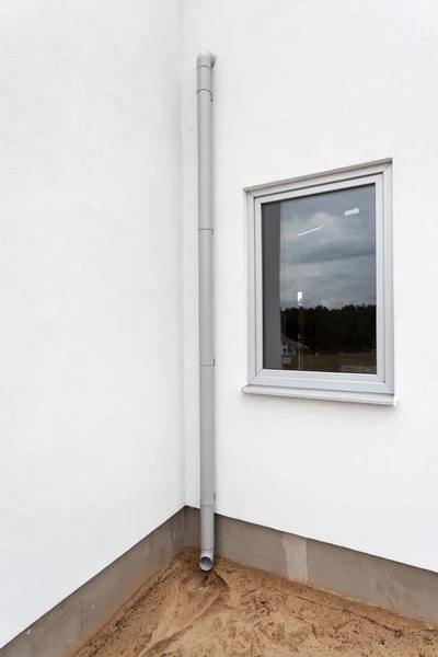 Nieuwe regengoot op een witte muur met venster. — Stockfoto