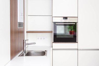 Yeni modern beyaz mutfak yapılı içinde fırın ve krom su ile dokunun.