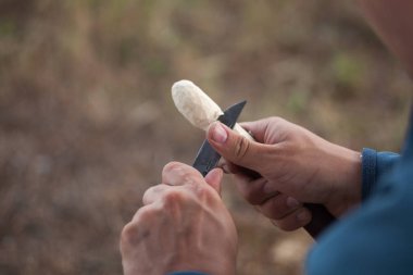 Bir tahta kaşık oyma bir bıçak ile çalışan adamın elleri uygun.