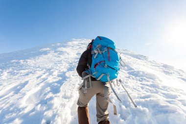 Mavi sırt çantası ile erkek turist karlı dağlarda yükselir. Kış aylarında Ukrayna Karpatlar.