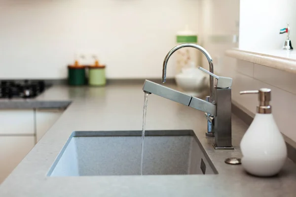 Rubinetto moderno dell'acqua cromato del progettista sopra il lavandino della cucina dell'acciaio inossidabile — Foto Stock