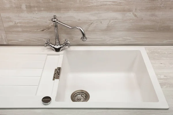 Modern designer chrome water tap over white kitchen sink