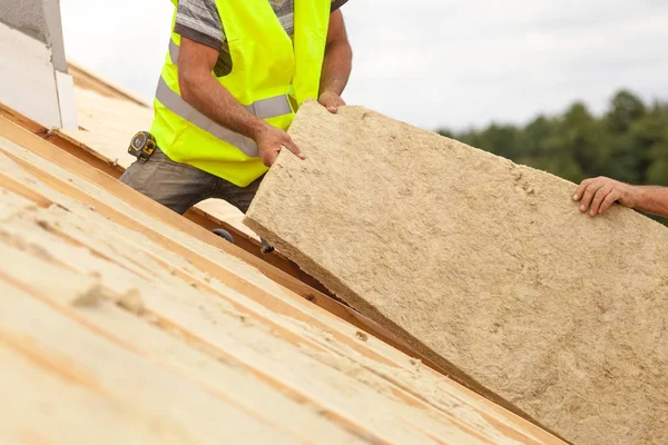 Travailleur du constructeur de toitures installant un matériau isolant sur la maison neuve en construction . — Photo