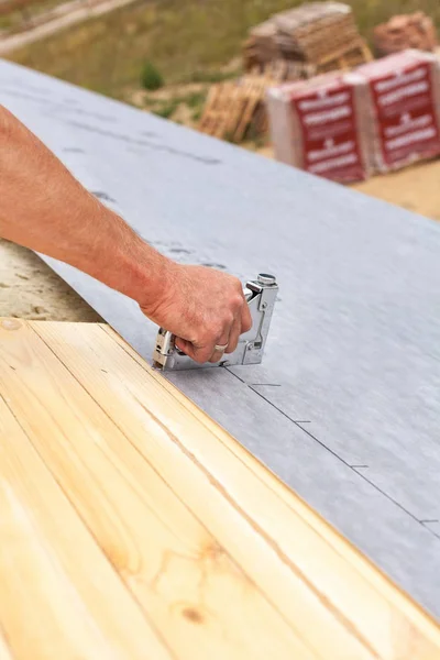 Roofer nails lining using construction stapler. Roof under construction. — Stock Photo, Image