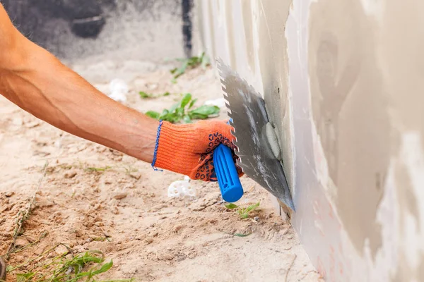 Trabajador de la construcción enlucido de una pared y cimentación de la casa con paleta . — Foto de Stock