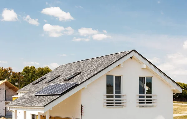 Solar water panel heating on new house roof with skylights against blue sky. — Stock Photo, Image