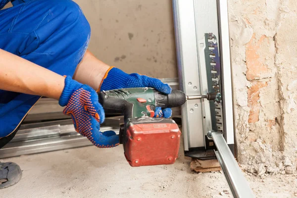 Garaj kapıları yükleme. Çalışan bir cıvata düzeltmek için otomatik tornavida kullanın. — Stok fotoğraf