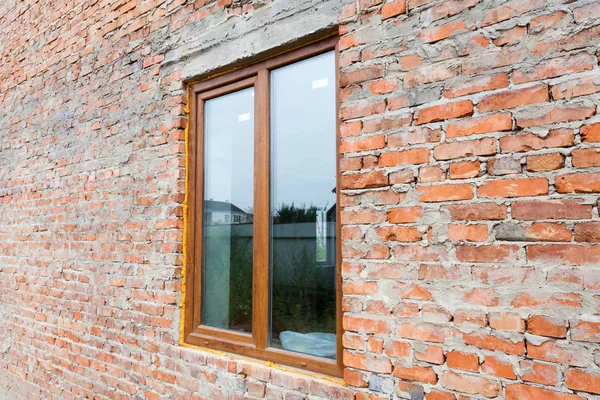 Single plastic window on a wall with red bricks. nstall window against brick wall facade