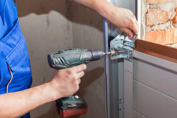 Instalação de portas de garagem.Trabalhador instalando sistema de elevação em perfil de metal com chave de fenda . — Fotografia de Stock