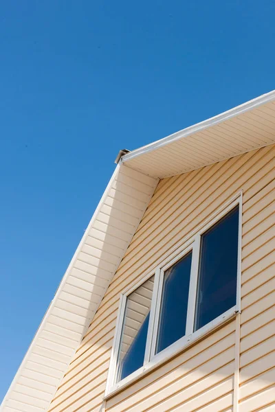 Una vista de ángulo bajo de los pisos superiores del techo de una casa durante el día contra el cielo azul . — Foto de Stock