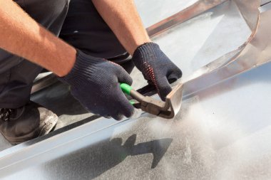 Çatı ustası Oluşturucusu alt kullanarak özel pense ile büyük bir düz kavrama bir sac katlama bitirme.