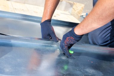 Çatı ustası Oluşturucusu alt kullanarak özel pense ile büyük bir düz kavrama bir sac katlama bitirme.