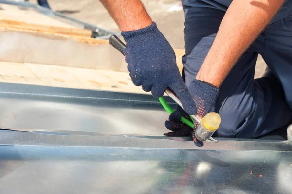 Roofer builder arbetare efterbehandling vika ett metall med gummiklubba. — Stockfoto