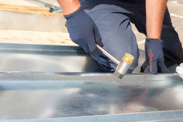 Roofer builder arbetare efterbehandling vika ett metall med gummiklubba. — Stockfoto