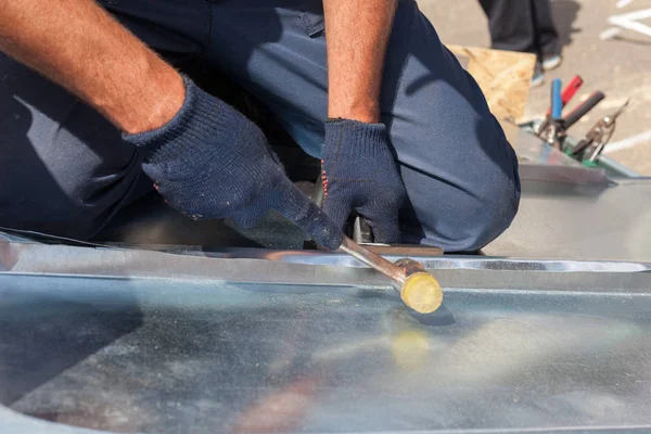 Ouvrier constructeur de toiture finition pliage d'une feuille de métal à l'aide de maillet en caoutchouc . — Photo