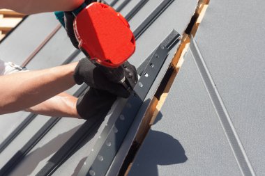 Elektrikli matkap yükleme metal bir çatı üzerinde çalışan döşeme ahşap ev.