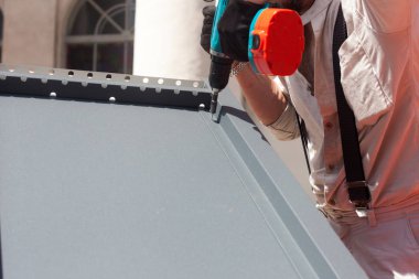 Elektrikli matkap yükleme metal bir çatı üzerinde çalışan döşeme ahşap ev.