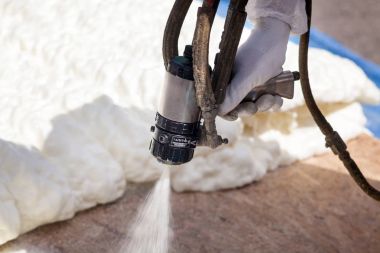 Technician spraying foam insulation using Plural Component Spray Gun. clipart