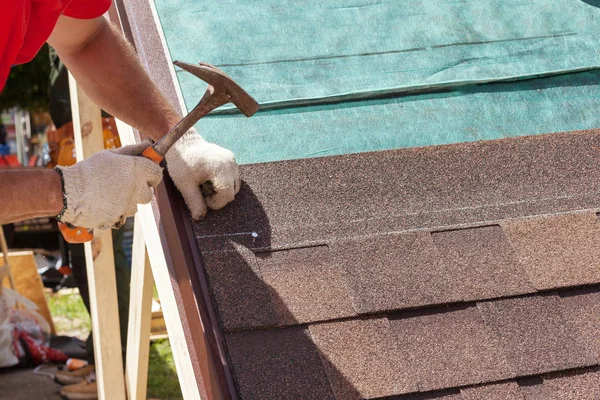 Roofer builder worker use a hammer for installing roofing shingles. — Stock Photo, Image