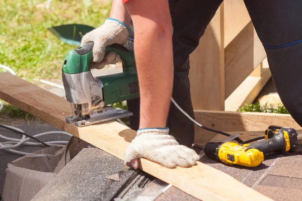 Schrijnwerker snijden van een stuk hout met behulp van een decoupeerzaag. — Stockfoto