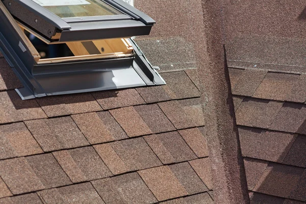 Nahaufnahme eines Dachfensters auf einem Dach mit Asphaltschindeln oder Bitumenziegeln im Bau. — Stockfoto