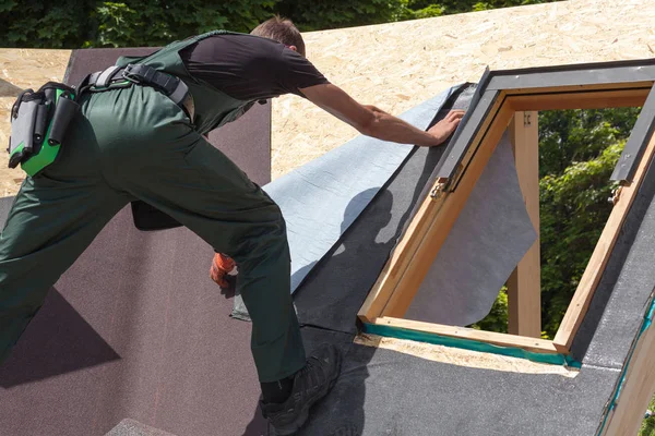 Roofer builder worker installing heating and melting bitumen roofing felt. Skylight. Roof window — Stock Photo, Image